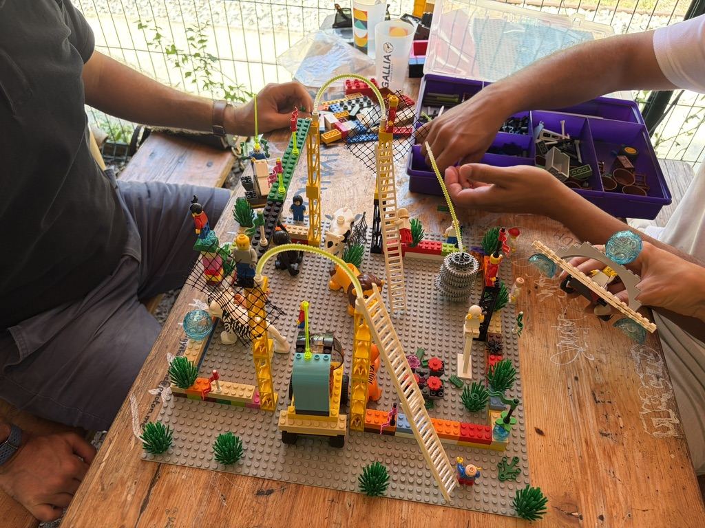 Les mains de plusieurs participants construisent ensemble une grande structure en briques