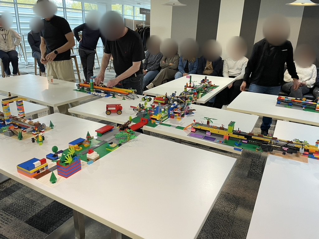 Un grand groupe construit une ville en briques sur plusieurs tables reliées